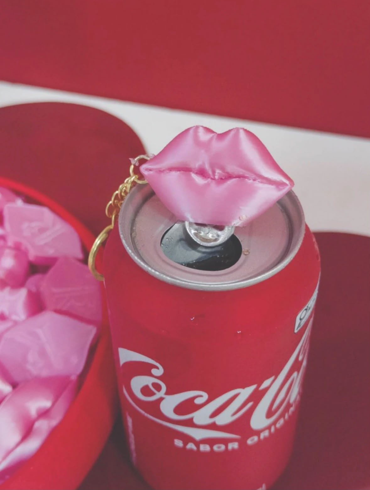 Pink lip can opener keychain on an open soft drink can