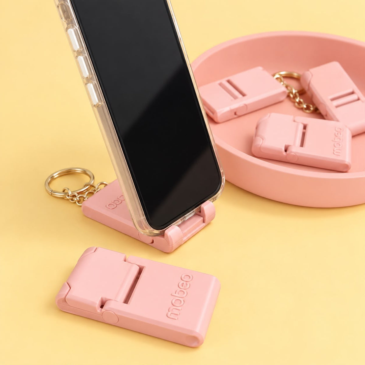 Pink phone stand keychain holding a phone